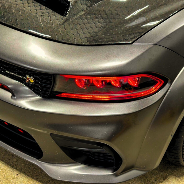 Custom Dodge Charger with aftermarket red LED headlights and matte gray wrap